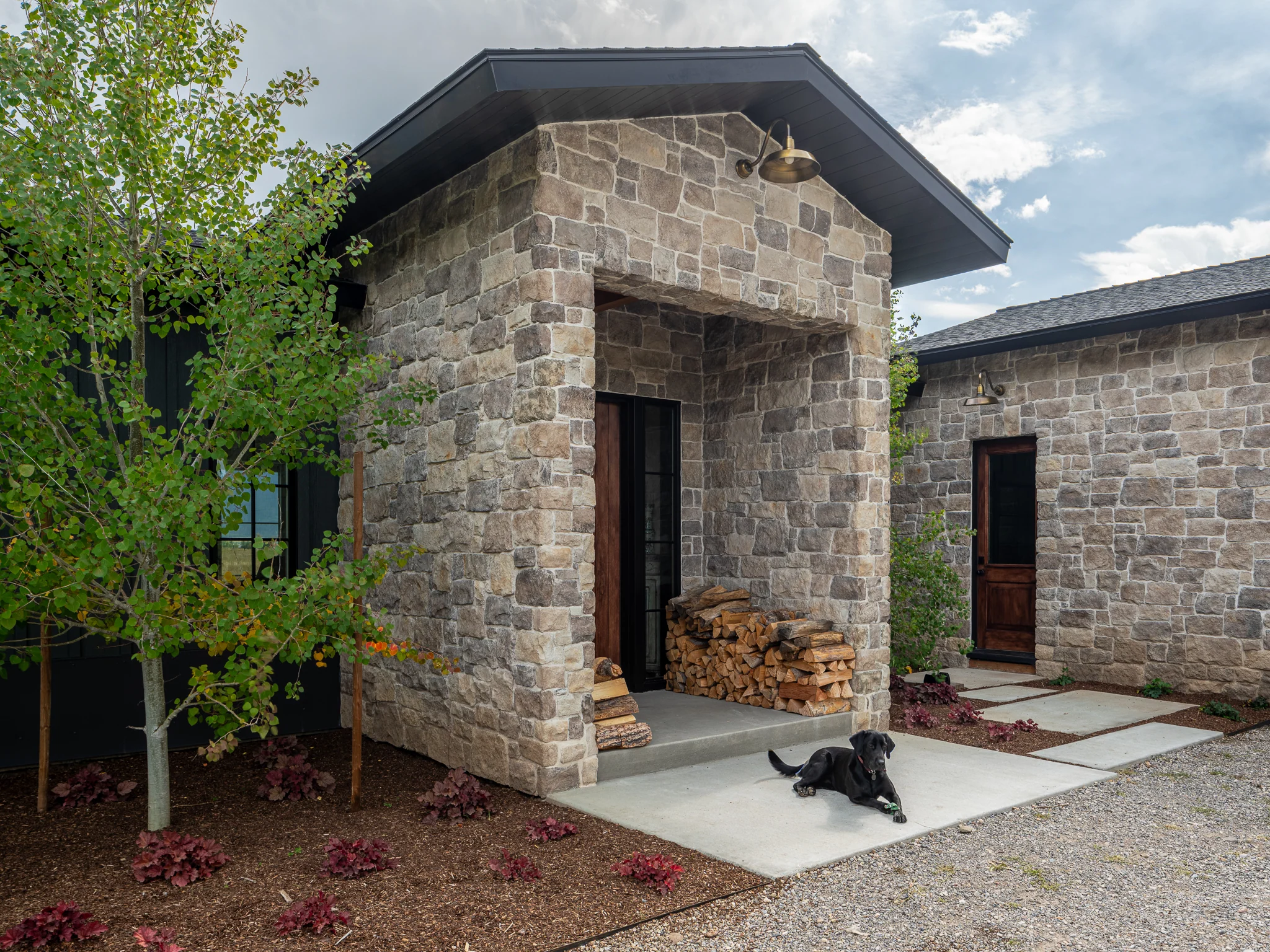 Stone entry breezeway with stacked firewood — architectural photography Driggs Idaho, River's Edge